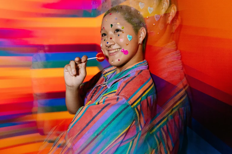 a man with brightly painted body standing next to rainbow wall