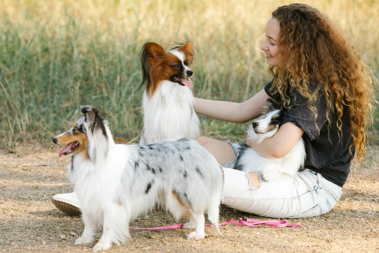 a woman is sitting with two dogs in her lap