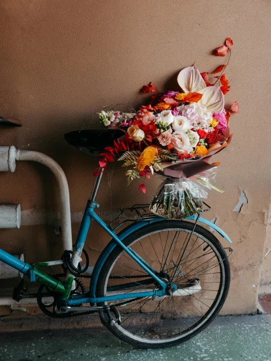 a bike with flowers is parked against a wall