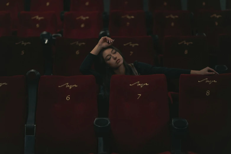 the woman is sleeping in the empty theater chair