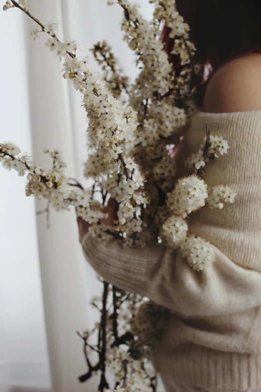 the woman is holding a plant up against her shoulders