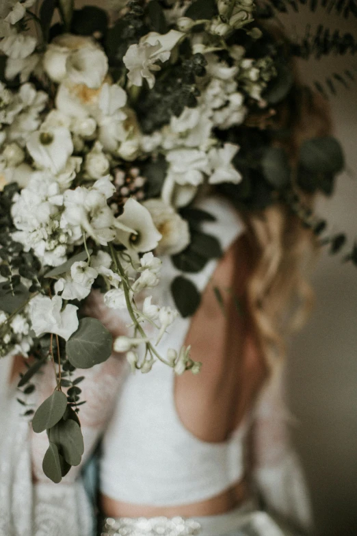 a woman with long hair and white dress holding a bouquet of flowers