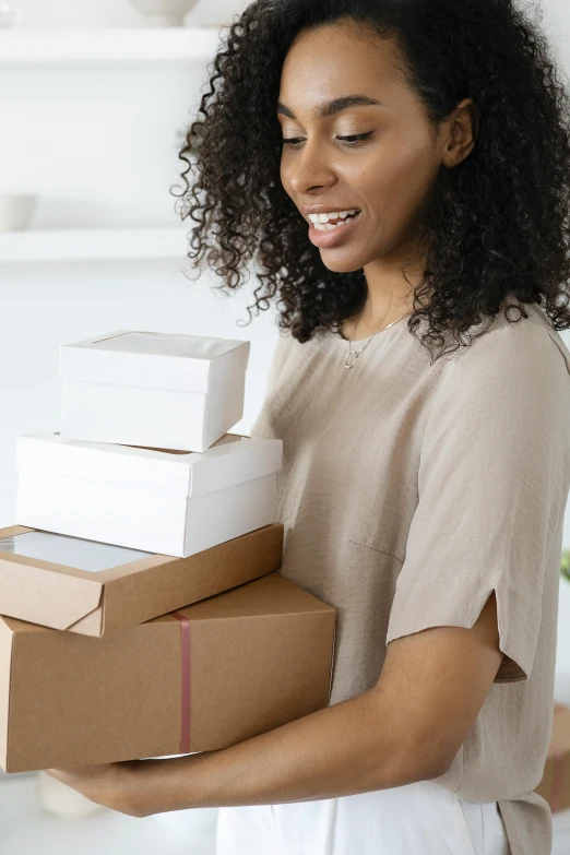 a woman with a box of supplies smiles while holding it