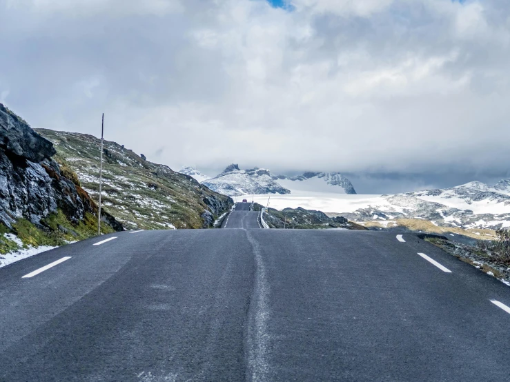 a car parked at the end of the road with mountains in the background