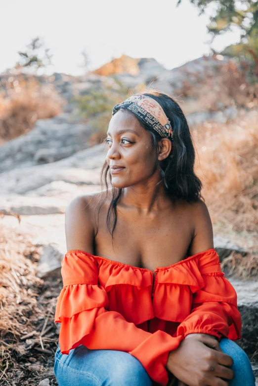 a woman in an orange top sitting on the ground