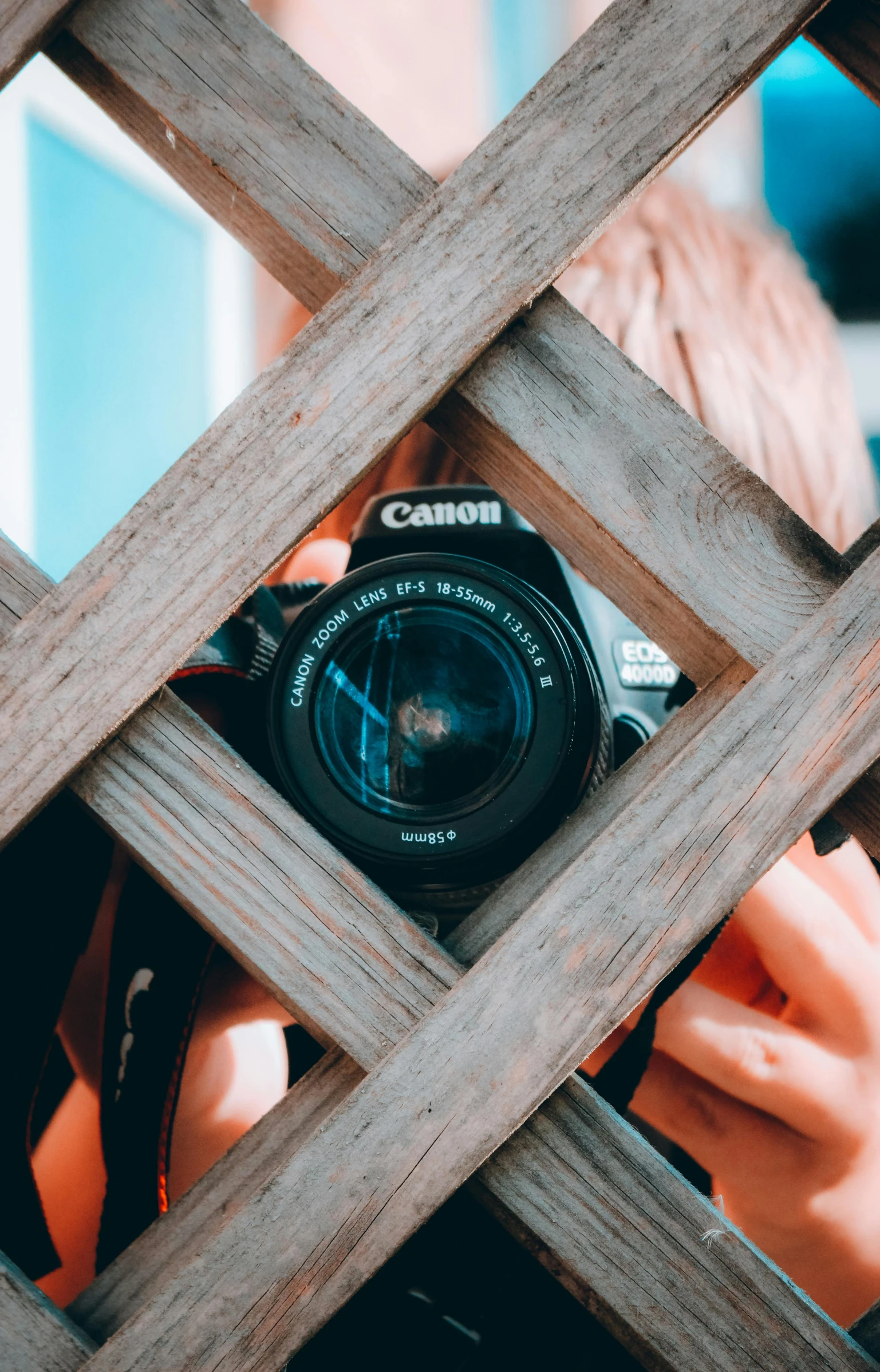 the girl takes a picture with her camera through the wooden bars