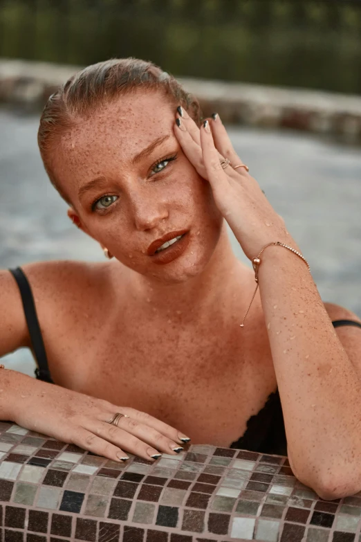 a young woman in a black bikini holds her hand to her head