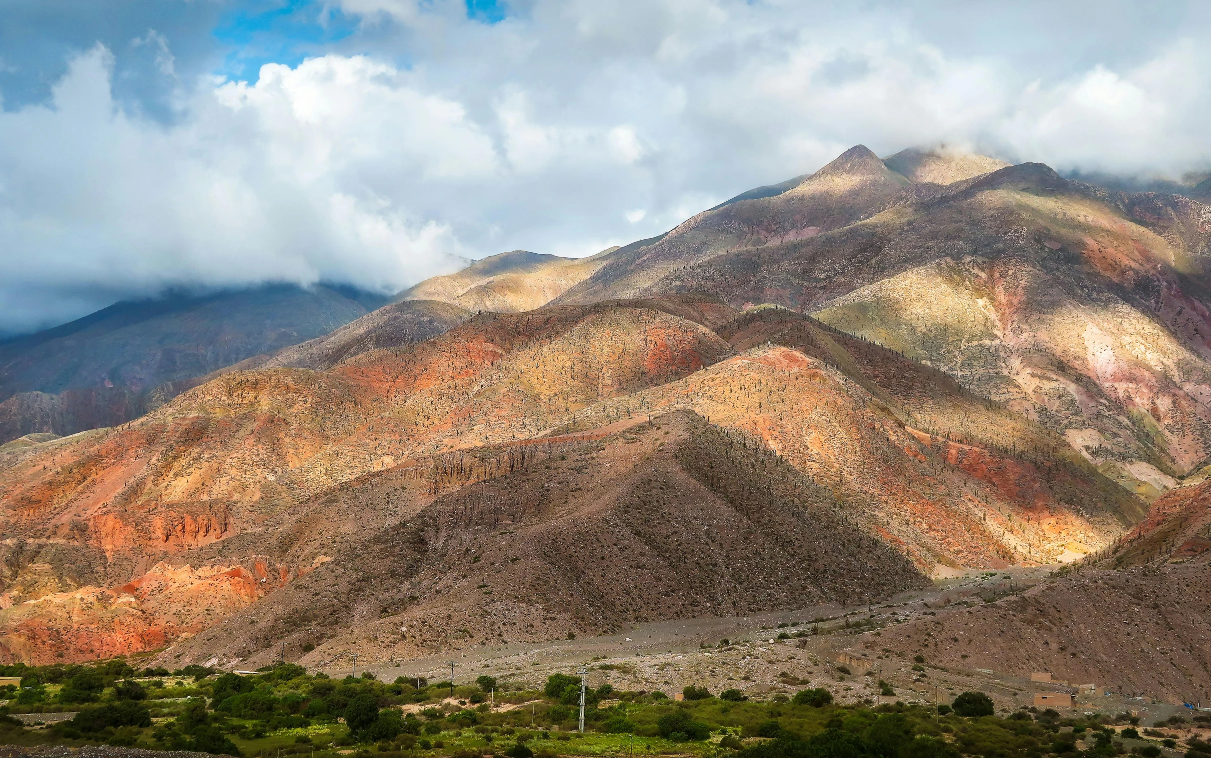 a mountain range in the desert under a cloudy sky