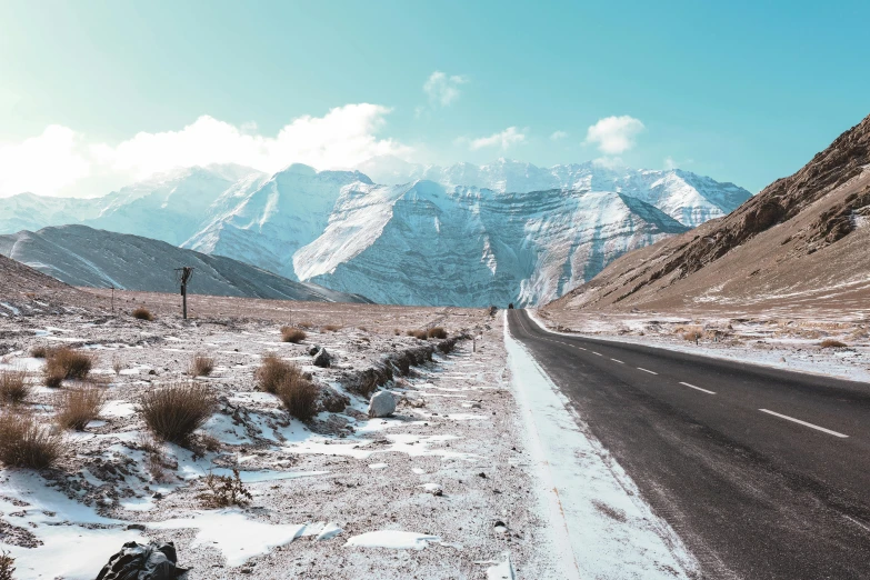 a mountain landscape with snow covering the road