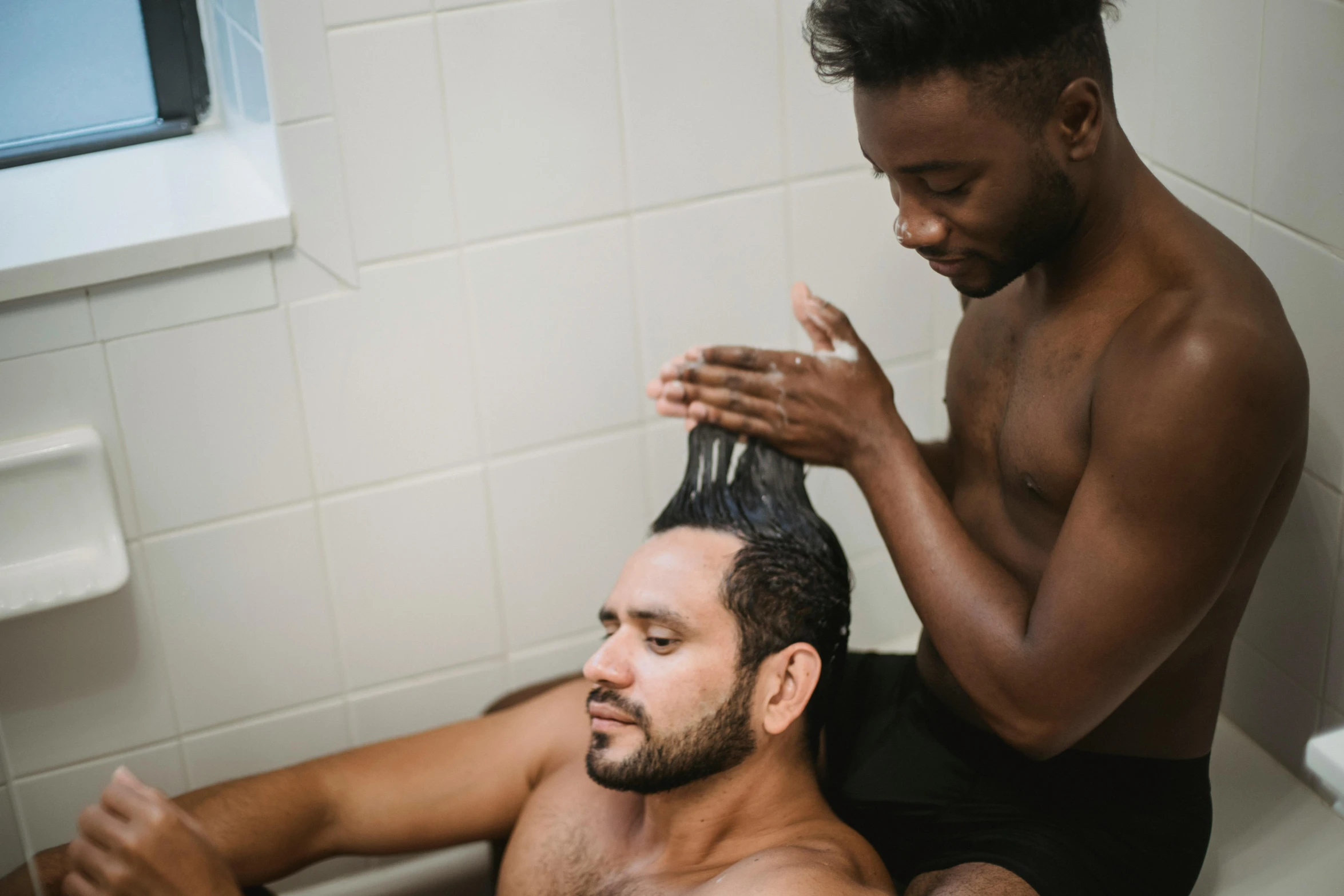 man getting hair washed in bath room near window