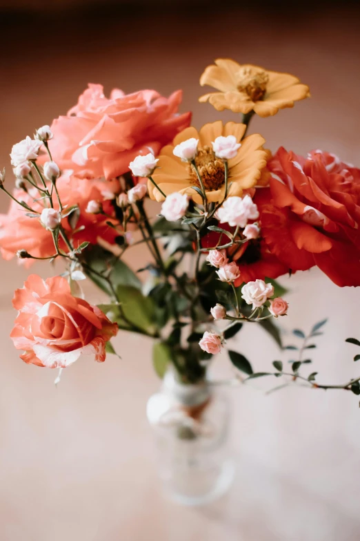 the flowers in the glass vase are red and yellow