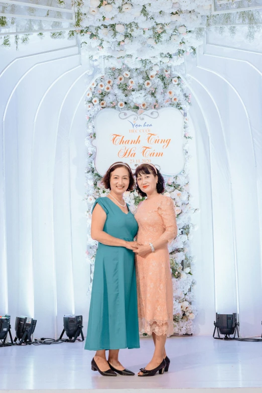 two women standing in front of a backdrop