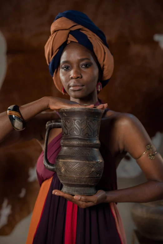 an african girl holding a large pot in her hands