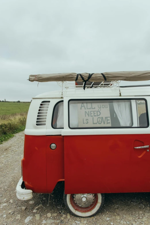 a red and white van on gravel with a surfboard on top