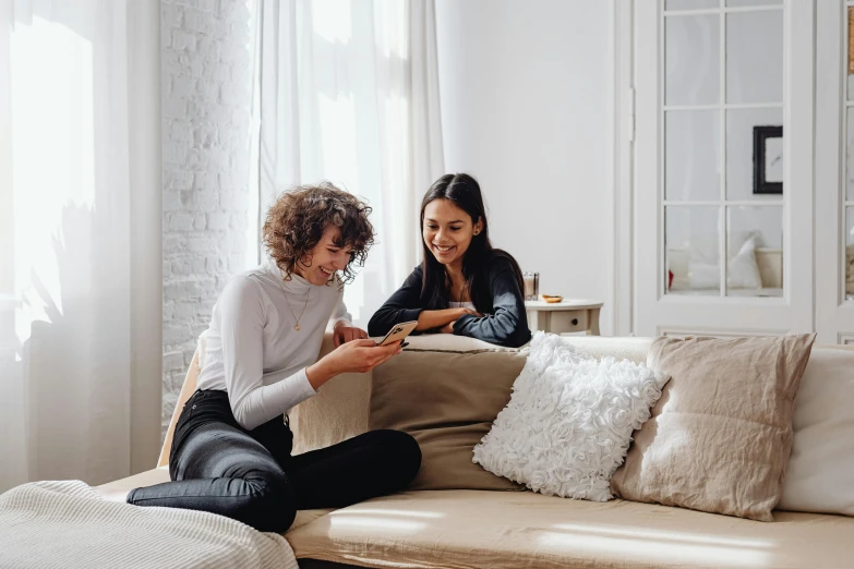 two women are on a couch one is reading soing