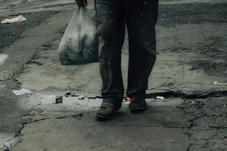 a person holding a large bag on top of a street