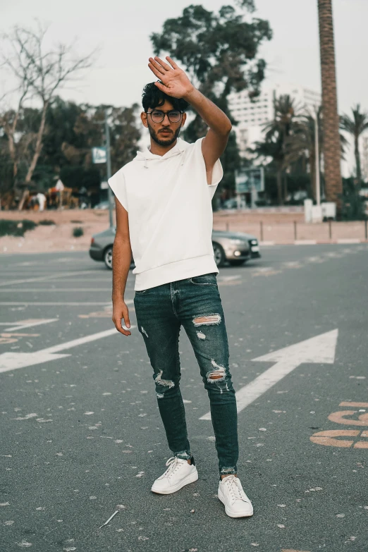 a man in ripped jeans and white shirt with white sneakers