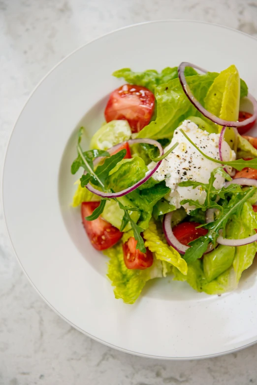 a plate of vegetables and a salad on a white table