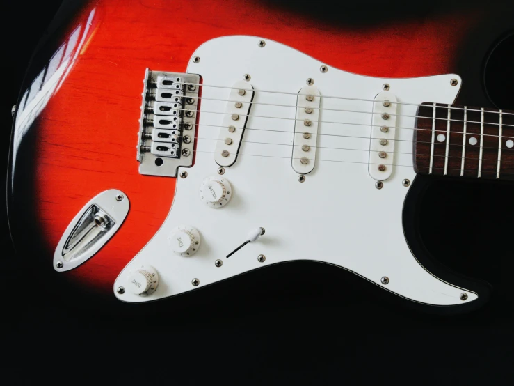 a red and white electric guitar is being displayed