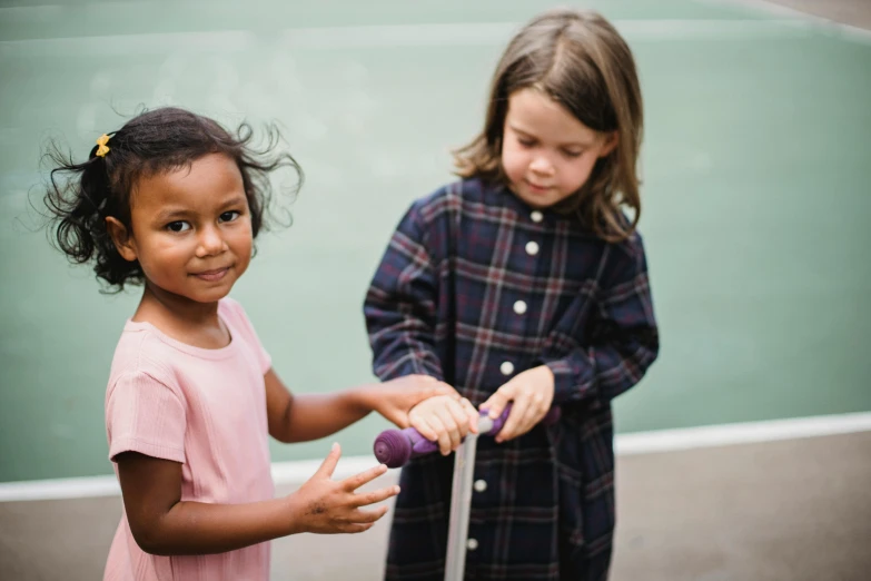 two little girls who are standing in front of a tennis court