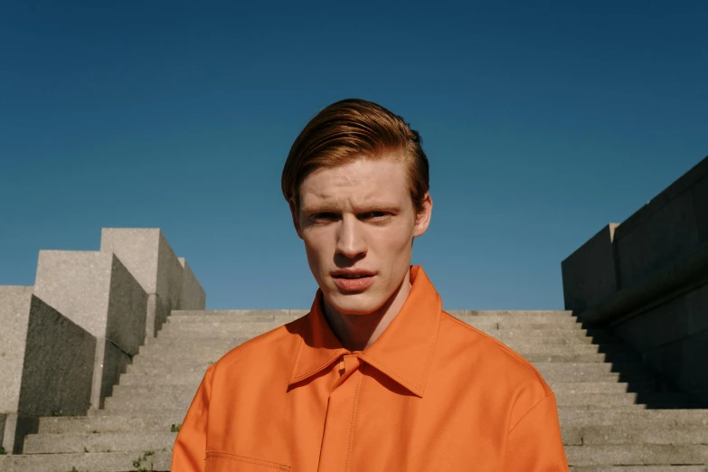 young man standing outside in orange shirt and orange pants