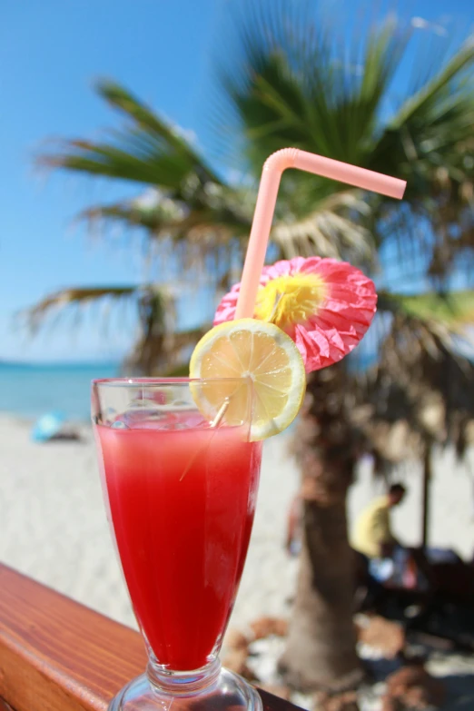 a beverage with a straw, a slice of lemon and a strawberry in a glass on a table