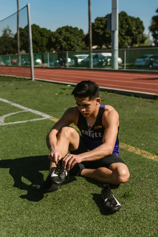 a man sitting on the ground while holding his shoe