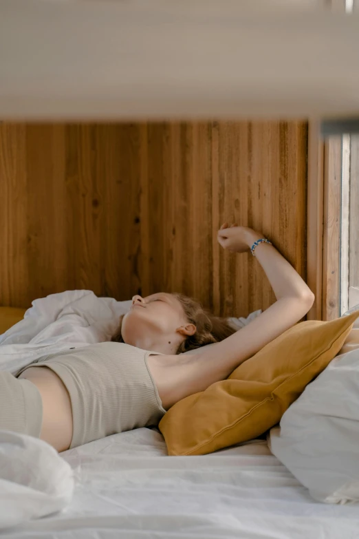 a woman laying in bed with her arm up on a pillow