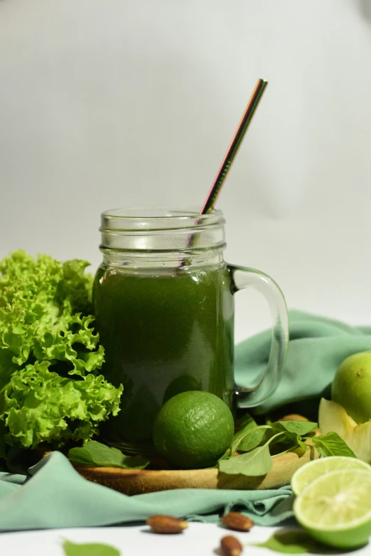there is a glass of fresh green juice and greens