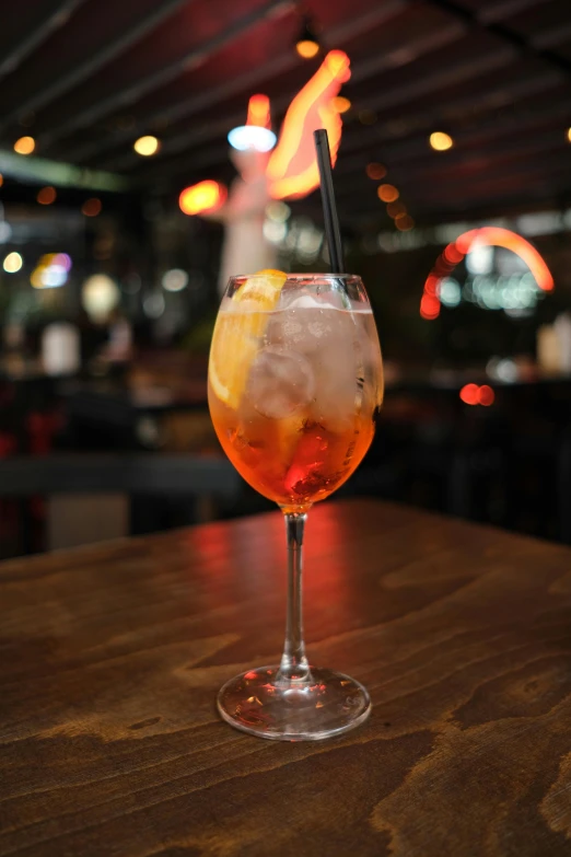 a wine glass with a drink garnish and a wooden table