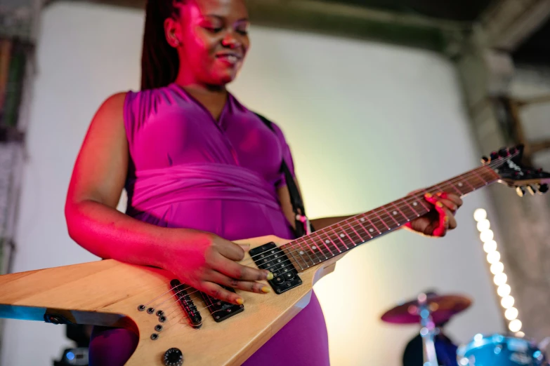 a woman in pink plays a guitar on a stage