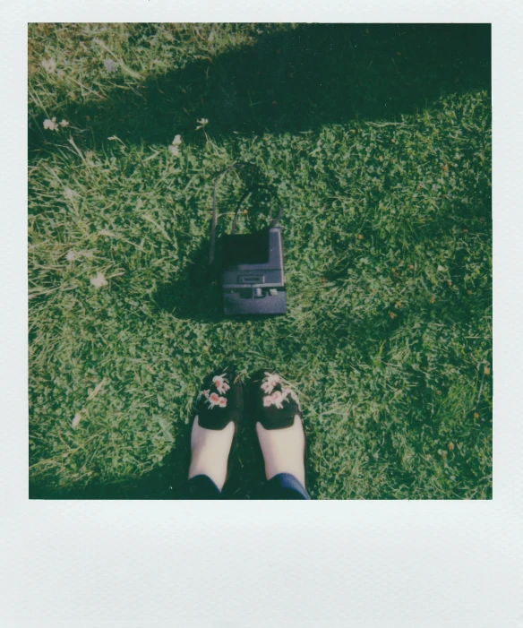 two persons feet wearing sandals and resting in the grass next to a laptop