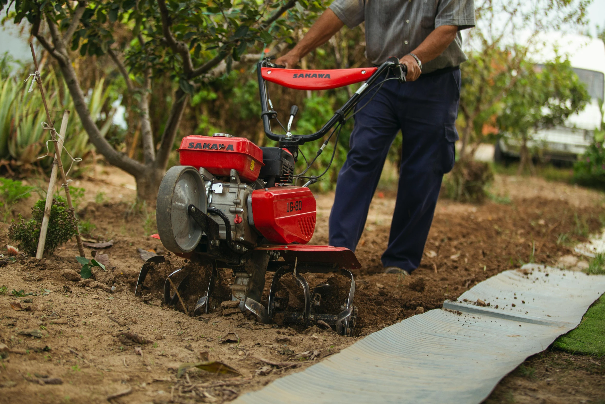 the man is weeding the lawn with his red tractor