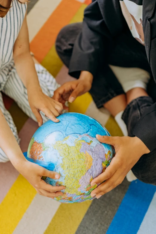 the child holds a globe and shows it to another child