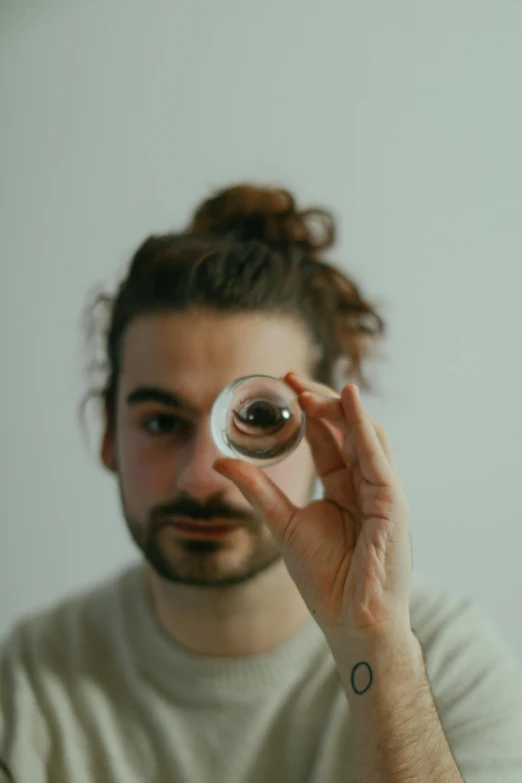 the man is holding a glass ball up to his face