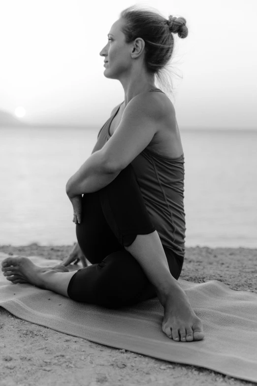 a woman in yoga clothes sitting on top of a towel