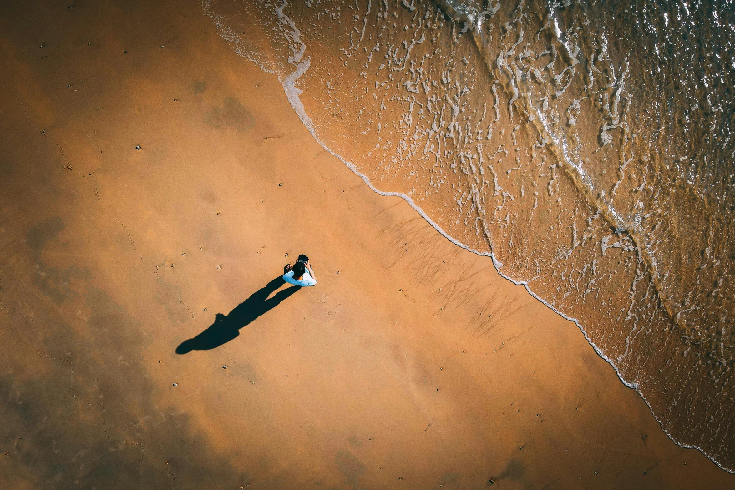 two people standing on the sand near the water