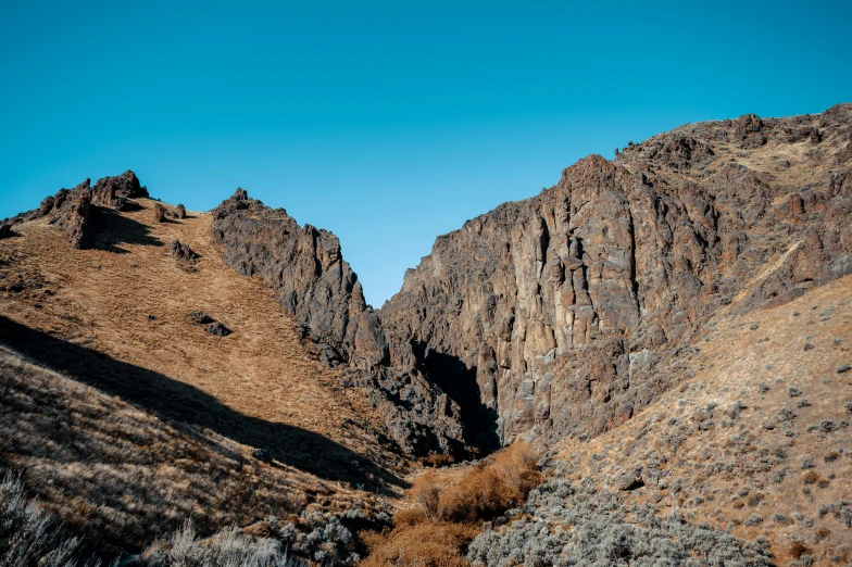 a mountain side with a rocky peak in the distance