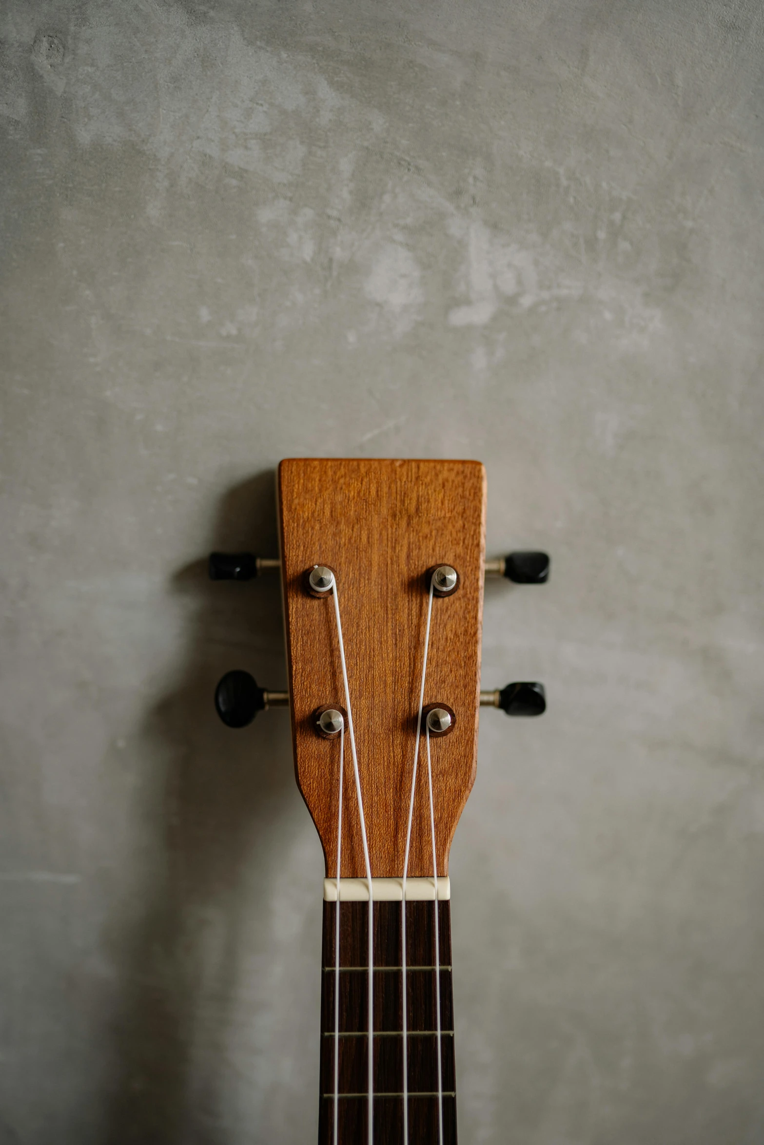 a brown guitar with a wooden neck on a wall