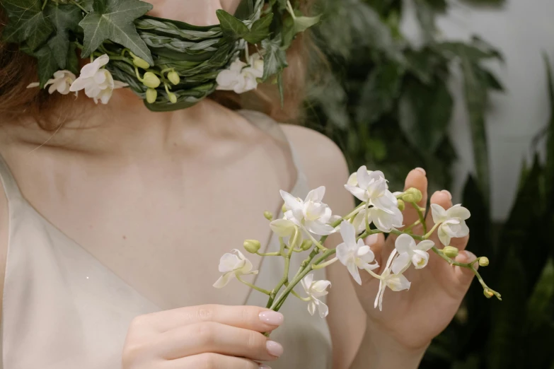 woman holding a flower crown over her face