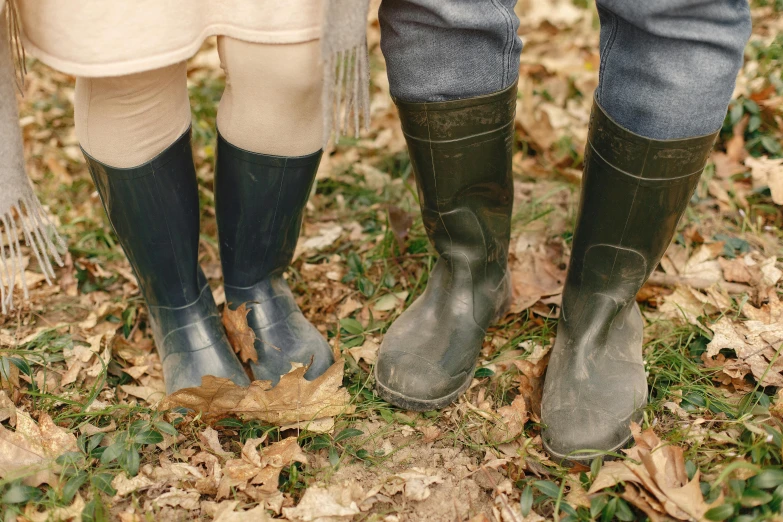 three women in boots are standing by some dry grass