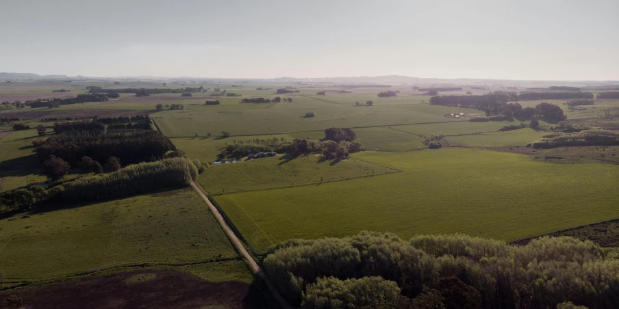 an aerial view of a green pasture in the far distance