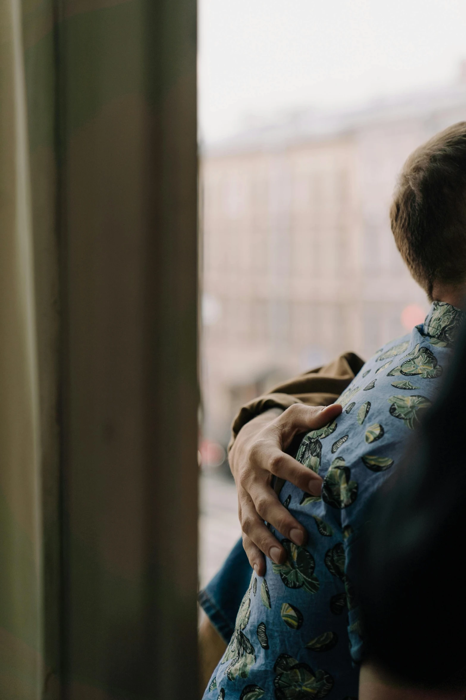 a man holding his son by the window in the day time