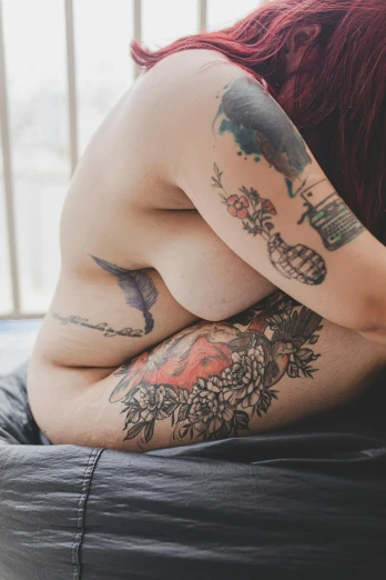 woman with big tattoo on her body lying  on bed