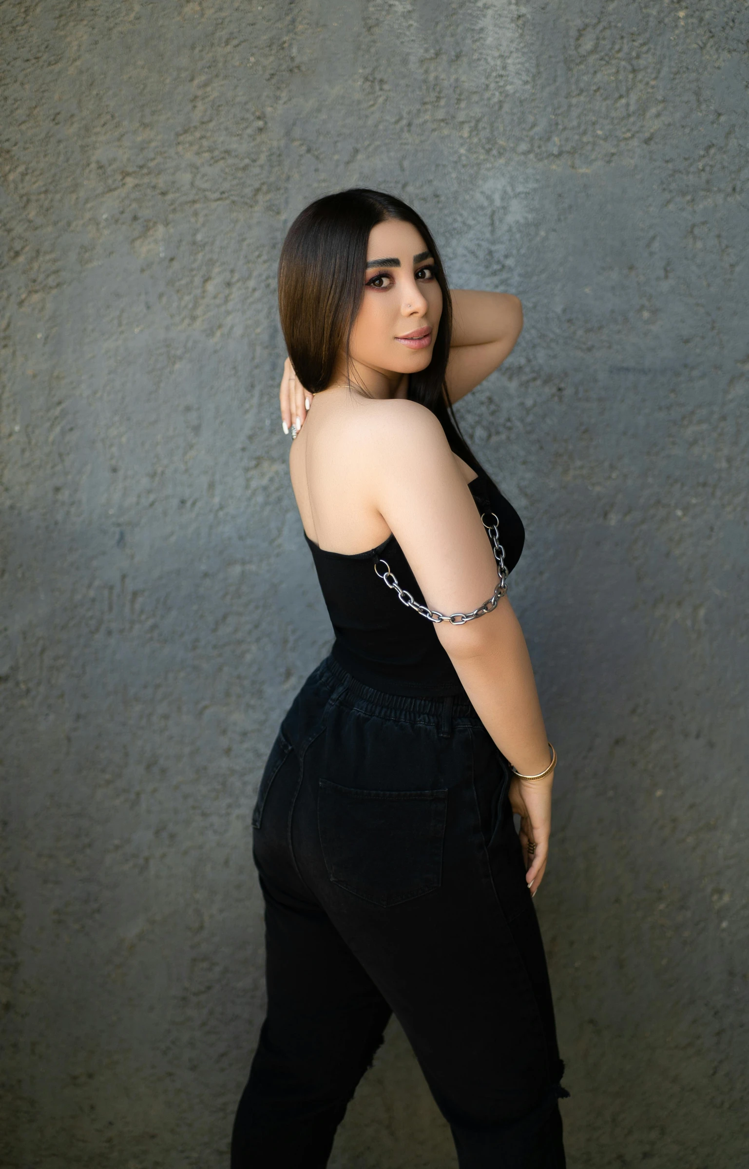 an indian woman standing next to a grey wall