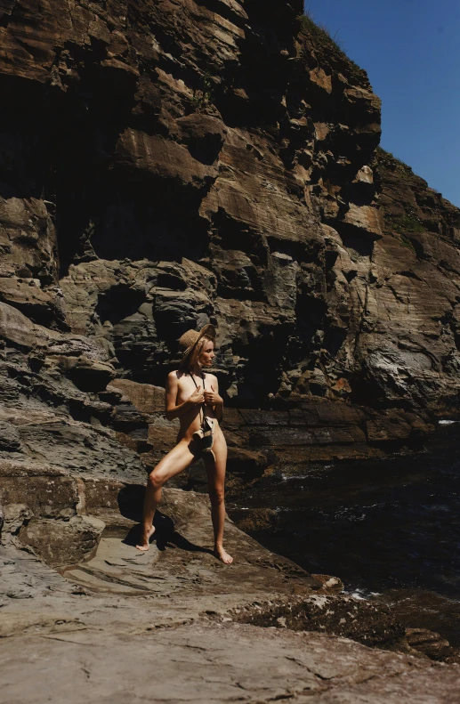 a girl standing on rocks near the ocean