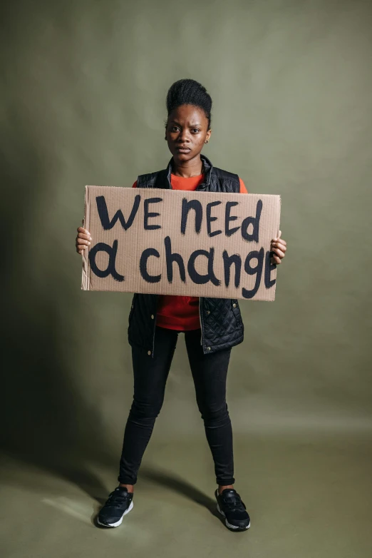 a woman holding up a sign reading we need a change