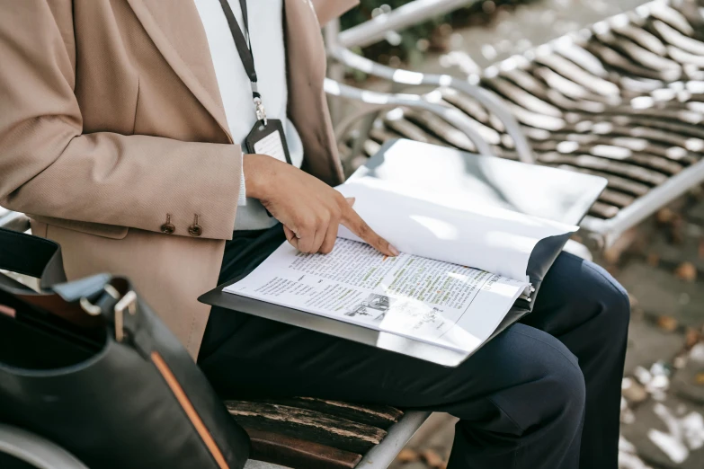 someone is sitting on the bench with an open book