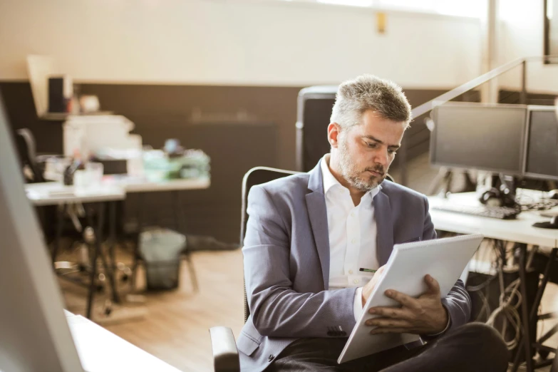 the man is writing on his clipboard while sitting at his office desk