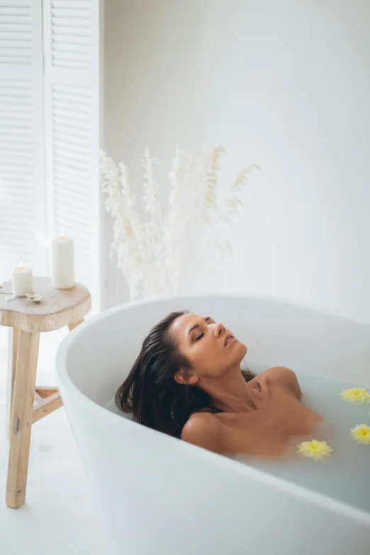 a woman taking a bubble bath in her white tub